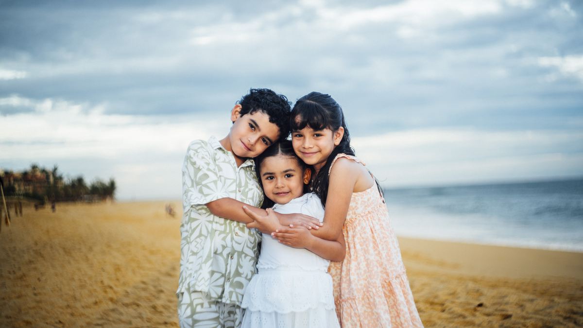 Los tres hijos de Michelle y Efrén abrazados en la playa.