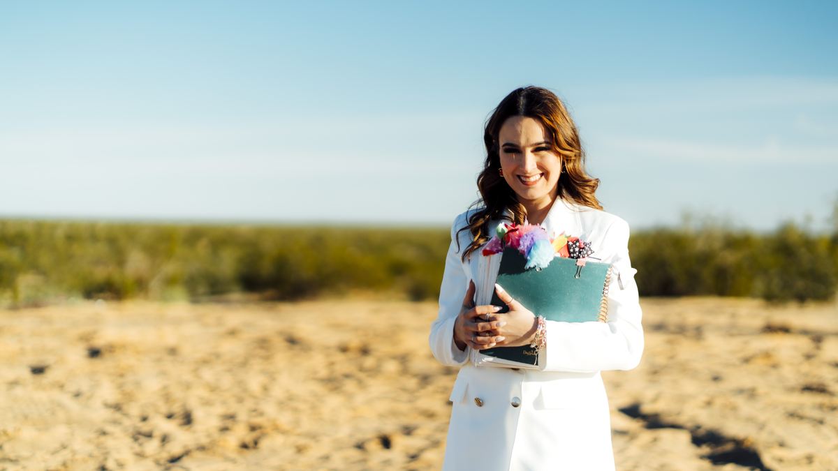 Retrato de Michelle Ruiz de blanco, sosteniendo su Biblia y un ramo de flores en el campo.