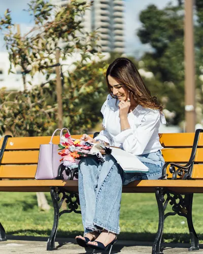 Michelle Ruiz sentada en una banca de parque, riendo, con su Biblia en el regazo.